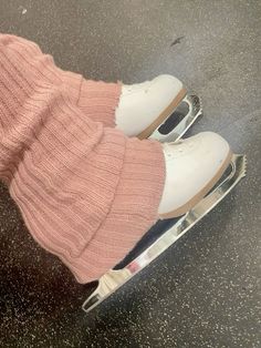 a pair of white shoes sitting on top of an ice skate covered in pink socks