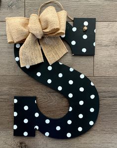 the letter s is made out of wood and has white polka dots with a bow on it