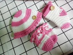 two crocheted pink and white baby booties sitting on top of a table