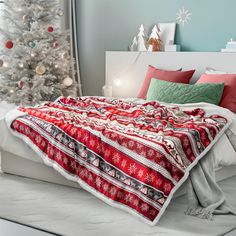 a bed with a red and white blanket next to a christmas tree