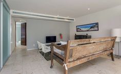 a wooden bench sitting in the middle of a living room next to a wall mounted tv