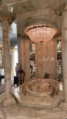 a large marble bathtub in the middle of a room with chandelier above it