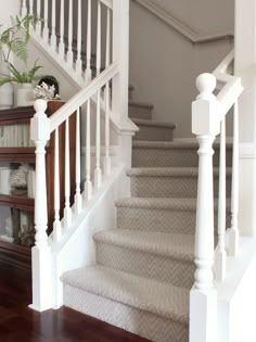 a staircase with white railings and wood flooring next to a bookshelf