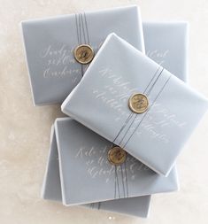 three blue gift boxes with gold buttons on them sitting on a marble counter top next to each other