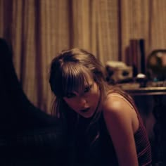 a young woman sitting on the floor in front of a table with a remote control