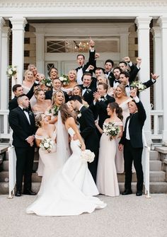 a large group of people standing in front of a white building with their arms up