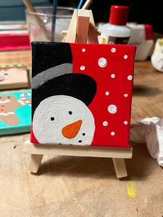 a snowman painted on an easel sitting on a table