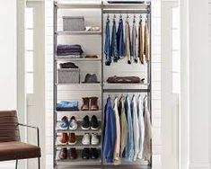 an organized closet with clothes and shoes on shelves in front of a window, next to a chair