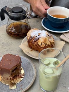 a table topped with desserts and drinks next to a cup of green tea on top of a plate