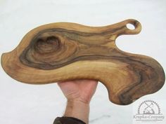 a hand holding a piece of wood that is shaped like an animal's head