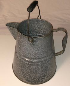 an old metal pitcher with a handle on the side and a small hook at the top