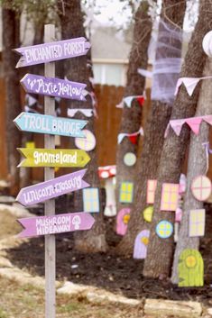 a wooden sign with many different colored signs on it's sides and trees in the background