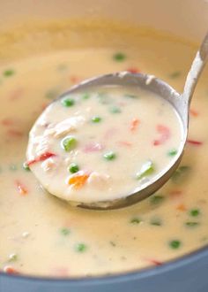 a spoon full of soup with peas and carrots