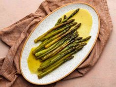 asparagus on a white plate with mustard sauce and a brown napkin next to it