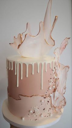 a pink and white cake with icing dripping from it's top on a table