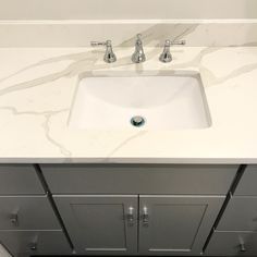 a bathroom sink with two faucets on top of it and marble counter tops