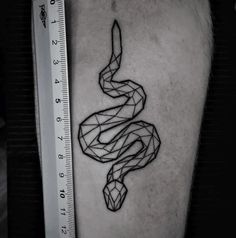 a black and white photo of a snake tattoo on the right thigh with a ruler