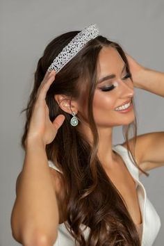 a woman wearing a tiara and holding her hair in one hand while smiling at the camera