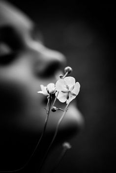 a black and white photo of a woman's face with flowers in her mouth