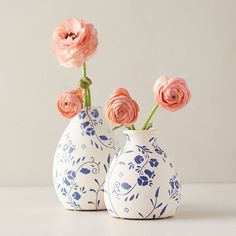 two blue and white vases with pink flowers in them