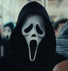 a person in a black hoodie with a ghost mask on and mouth wide open