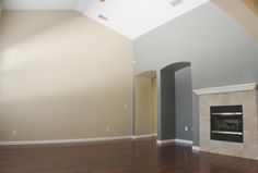 an empty living room with wood floors and a fireplace in the middle of the room