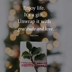 a present wrapped in red and white paper with a christmas tree in the background that says, enjoy life it's a gift unwrap it with grateful and love