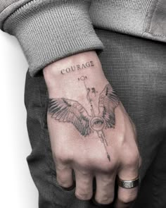 a man's hand with a tattoo on it and the words courage written in black ink