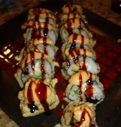 there are many sushi rolls with sauce on them sitting on the grill grate