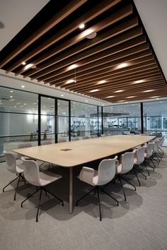 an empty conference room with white chairs and wooden ceilinging, along with glass walls