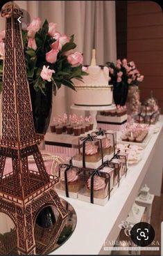 the dessert table is set up with pink roses and cupcakes in front of the eiffel tower