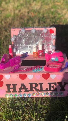 an assortment of cosmetics and nail polish in a pink box on the grass with hearts