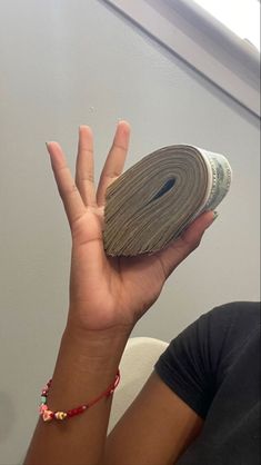 a person holding up a roll of paper with one hand and the other on top of it