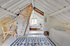 an attic bedroom with white walls and wood flooring is furnished with natural materials such as exposed brick