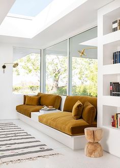 a living room filled with lots of furniture next to a window covered in bookshelves