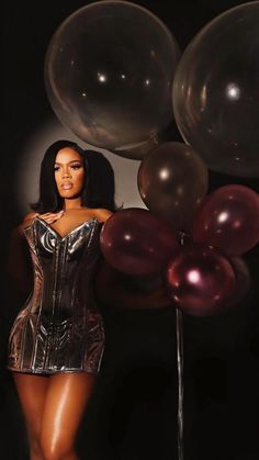 a woman in a silver corset with balloons behind her on a black background