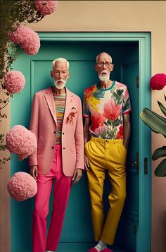 two older people standing in front of a blue door with pink flowers on the ground