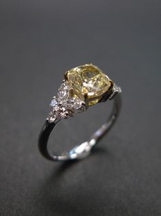 an engagement ring with three diamonds on the top and one yellow diamond in the middle