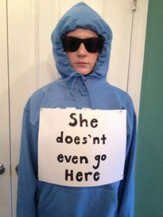 a person in a blue hoodie holding a sign that says she doesn't even go here