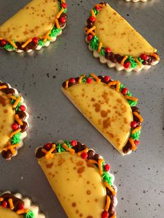 several decorated cookies sitting on top of a cookie sheet in the shape of tacos