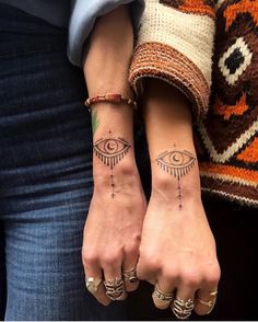 two people with matching tattoos on their arms and wrist, both holding each other's hands