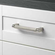 a close up of a drawer handle on a white cabinet with black counter top and drawers