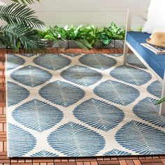 a blue and white area rug sitting on top of a wooden floor next to a plant