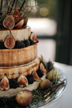 a three tiered cake with figs and berries on it