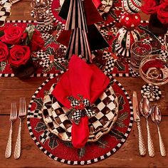 the table is set with red roses and black and white checkered placemats