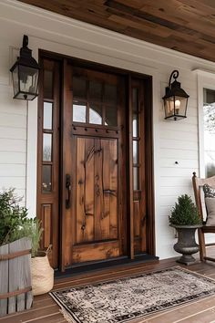 a wooden door sitting on the side of a white house next to a chair and potted plant