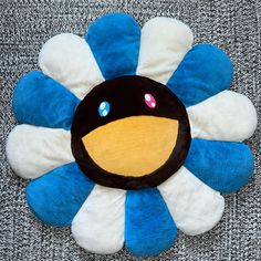 a blue, white and black flower shaped object on a gray surface with other items in the background