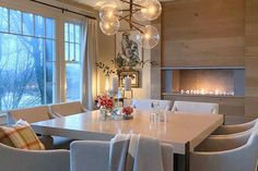 a dining room table with white chairs and a chandelier hanging from the ceiling