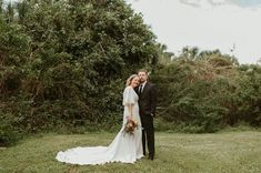 a bride and groom pose for a photo in front of some trees on their wedding day