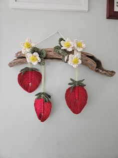 three strawberries are hanging on a branch with daisies in the center and white flowers at the top